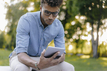 Young man looking at cell phone in park - KNSF03193