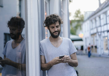 Mann schaut in der Stadt auf sein Handy - KNSF03201