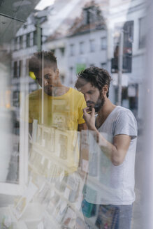 Zwei Freunde in der Stadt schauen in das Schaufenster eines Buchladens - KNSF03202