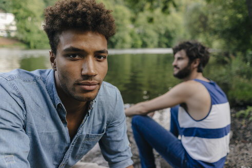 Porträt eines jungen Mannes mit einem Freund, der sich am Wasser entspannt - KNSF03209