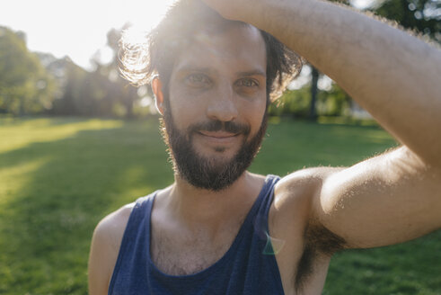 Porträt eines lächelnden Mannes mit Bart bei Sonnenuntergang in einem Park - KNSF03220