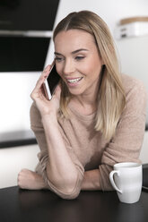 Portrait of blond woman on the phone at home - GDF01173