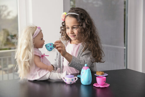 Portrait of smiling little girl playing with doll and doll's china set - GDF01179