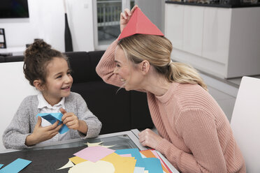 Mutter und kleine Tochter basteln mit buntem Papier und haben Spaß dabei - GDF01192