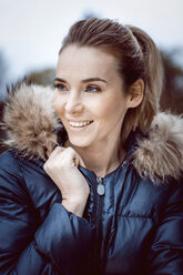 Portrait of smiling woman wearing winter jacket with fur collar - GDF01196