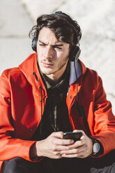 Italy, Verona, tourist with smartphone and headphones - GIOF03570