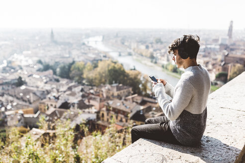 Italien, Verona, Tourist mit Smartphone, Kopfhörer - GIOF03583