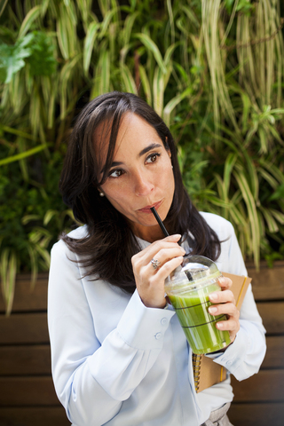 Frauen trinken grünen Saft, Entgiftung, Plastikbecher, lizenzfreies Stockfoto