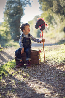 Junge mit Steckenpferd auf Holzkiste sitzend - XCF00162