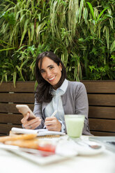 Porträt einer lächelnden Geschäftsfrau, die in einem Straßencafé arbeitet - VABF01392
