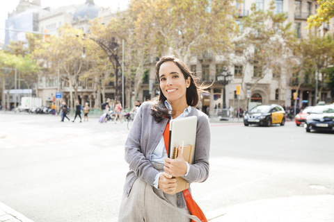 Porträt einer lächelnden Frau mit Notebook in der Stadt, lizenzfreies Stockfoto