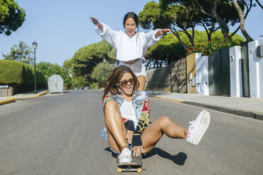 Zwei lachende Freunde zusammen auf dem Skateboard - KIJF01743