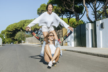 Two laughing friends together on skateboard - KIJF01745