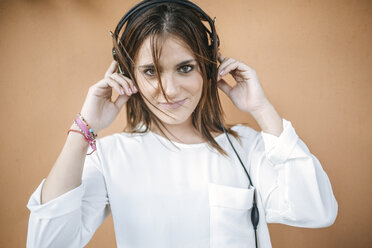 Porträt einer lächelnden jungen Frau, die mit Kopfhörern Musik hört - KIJF01756