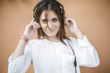 Portrait of smiling young woman listening music with headphones - KIJF01756