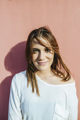 Portrait of smiling young woman leaning against wall - KIJF01766