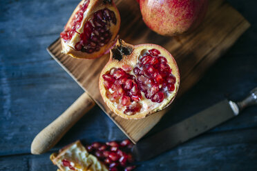 Sliced and whole pomegranate on cutting board - KIJF01771