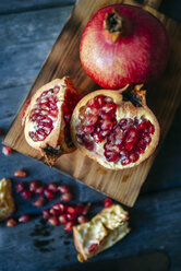 Sliced and whole pomegranate on cutting board - KIJF01772