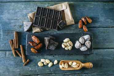 Dates, dark chocolate, almonds, cinnamon sticks and dried figs on wood - KIJF01782