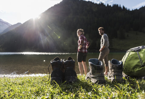 Österreich, Tirol, Wanderschuhe und Paar beim Erfrischen im Bergsee - UUF12476