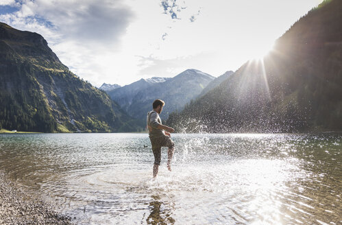 Austria, Tyrol, hiker splashing in mountain lake - UUF12478