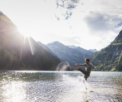 Austria, Tyrol, hiker splashing in mountain lake - UUF12479