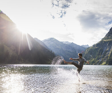 Österreich, Tirol, Wanderer plantscht im Bergsee - UUF12479