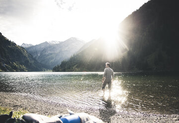 Österreich, Tirol, Wanderer erfrischt sich in Bergsee - UUF12482