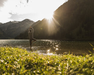 Austria, Tyrol, hiker in yoga pose refreshing in mountain lake - UUF12486
