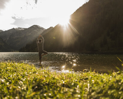 Österreich, Tirol, Wanderer in Yogapose beim Erfrischen im Bergsee - UUF12486
