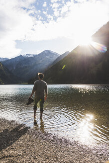 Österreich, Tirol, Wanderer erfrischt sich in Bergsee - UUF12488