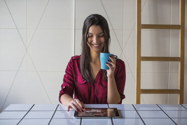 Woman looking at tablet computer and smiling - MOMF00335