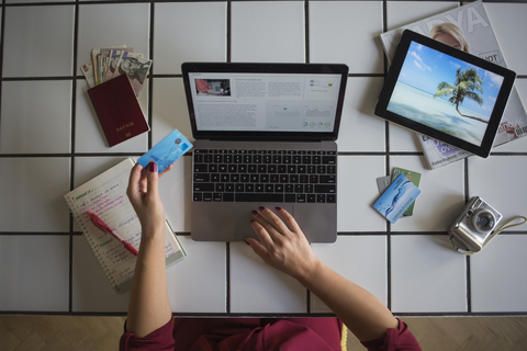 Junge Frau benutzt Laptop, bezahlt mit Kreditkarte, Reisebuchung, lizenzfreies Stockfoto