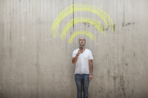 Mann hält Handy mit gelber Kreide wifi Zeichen über seinem Kopf - ZEF14872