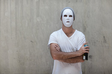 Mann mit Maske steht neben einer Betonwand und hält eine Spraydose in der Hand - ZEF14881