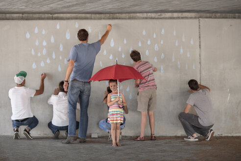 People drawing raindrops on concrete wall, little girl standing holding red umbrella - ZEF14892