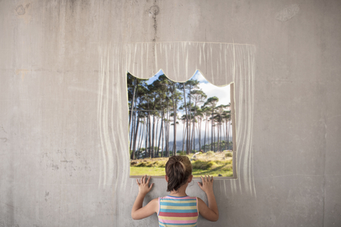 Girl holding a picture of a forest on concrete wall with a chalk drawn border stock photo