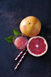 Whole and sliced Pink Grapefruit, leaves, straws and glass of grapefruit juice - CSF28593