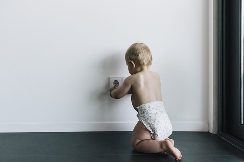 Baby berührt ungesicherte Steckdose, lizenzfreies Stockfoto