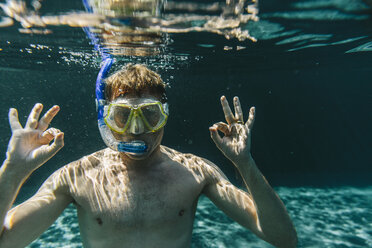 Portrait of man with diving goggles and snorkel underwater in a swimming pool making ok sign - MFF04237