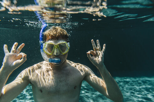 Porträt eines Mannes mit Taucherbrille und Schnorchel unter Wasser in einem Schwimmbad, der ein Ok-Zeichen macht - MFF04237