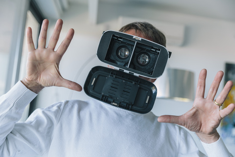 Verwirrter Mann mit VR-Brille macht ein verrücktes Gesicht, lizenzfreies Stockfoto