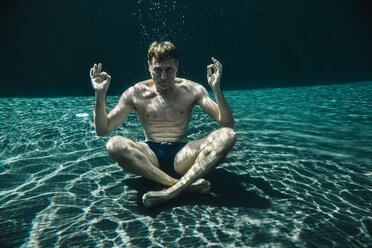 Mann in Yogastellung unter Wasser im Schwimmbad sitzend - MFF04254