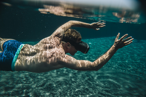 Mann taucht in einem Schwimmbad mit VR-Brille, lizenzfreies Stockfoto