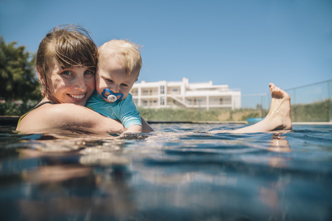 Porträt einer lächelnden Mutter mit ihrem kleinen Sohn im Schwimmbad, lizenzfreies Stockfoto