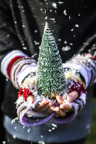 Girl's hands holding a toy Christmas tree, close up stock photo