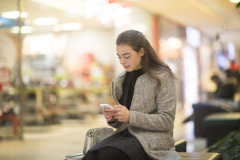 Junge Frau benutzt Smartphone in einem Geschäft - SGF02129