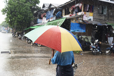Myanmar, Rückenansicht eines Mannes unter einem Regenschirm im Regen - IGGF00251
