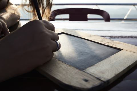 Frau schreibt auf Kreidetafel, Nahaufnahme, lizenzfreies Stockfoto