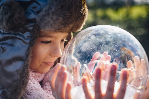 Brother and sister looking into crystal ball filled with snow, making a wish - MJF02213